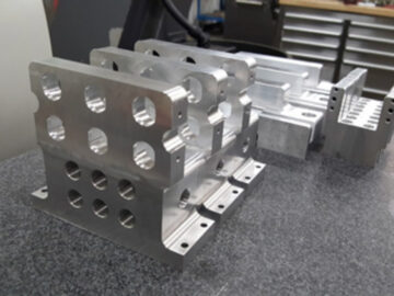 Stacked aluminum fixture components with precise holes and cuts for industrial applications.